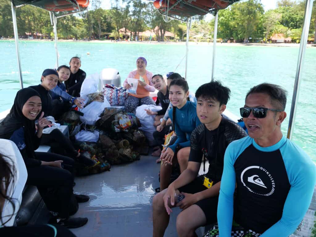 Divers on boat pose with several large bags of ocean debris collected during their time in the water 