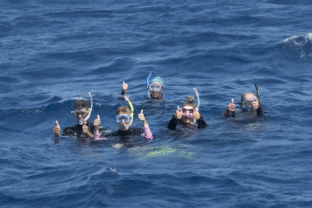 Snorkelers giving thumbs up above surface in open ocean water